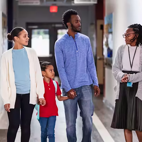 A family touring hallway of a school guided by principal.