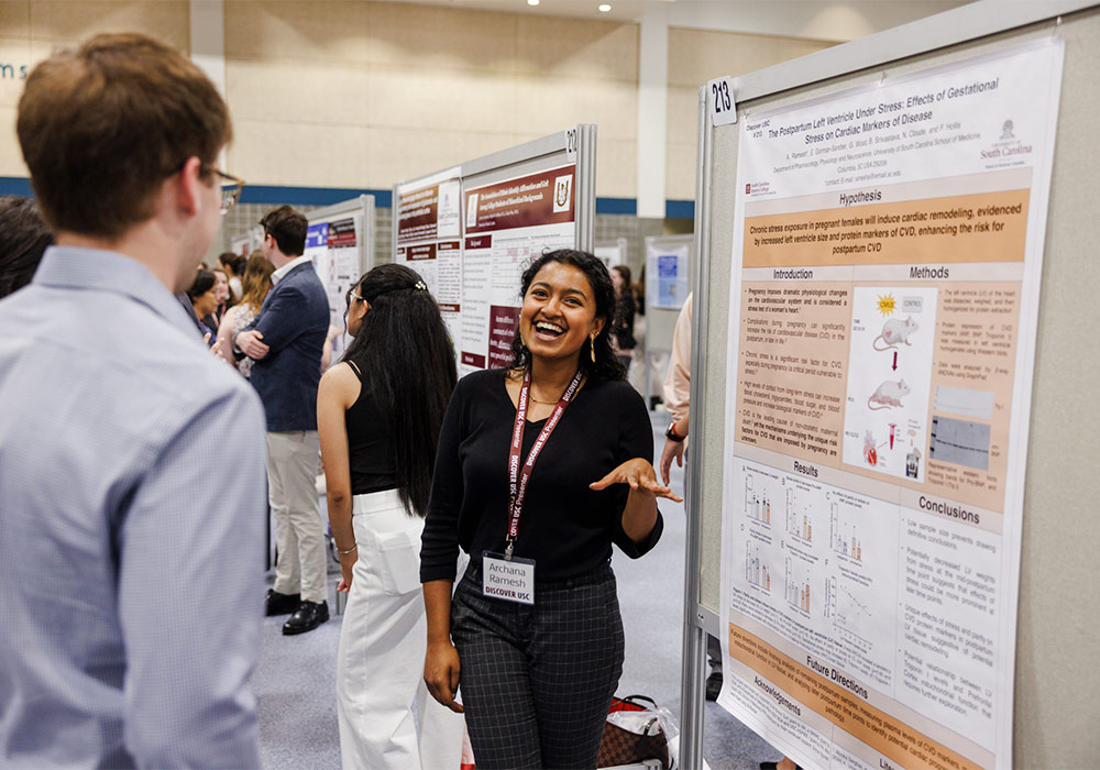 a female student stands in front of her poster at discover USC
