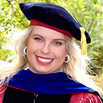 Head and shoulders photo of Zoie Horecny in her Ph.D cap and gown