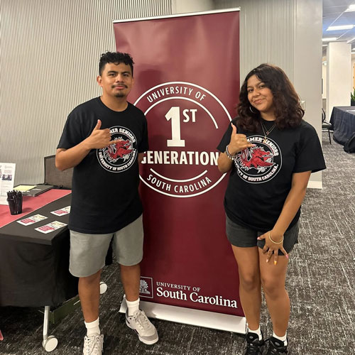 Man and woman standing in front of a virtical garnet banner 