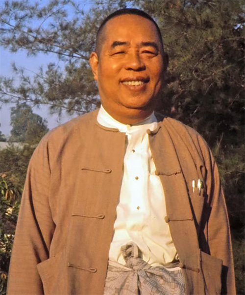 Middle-aged Asian man smiling in brown coat over white shirt
