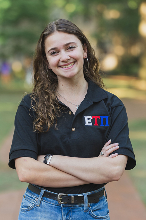 Ashley Chittum smiles on USC's historic Horseshoe while wearing a black Polo shirt featuring the letters for Epsilon Tau Pi, the service fraternity for Eagle Scouts
