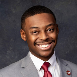 A headshot of Jordan Richardson in a suit and tie