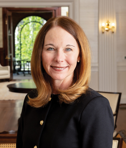 Dolly Garfield poses for a close up portrait in a formal room wearing a black shirt.