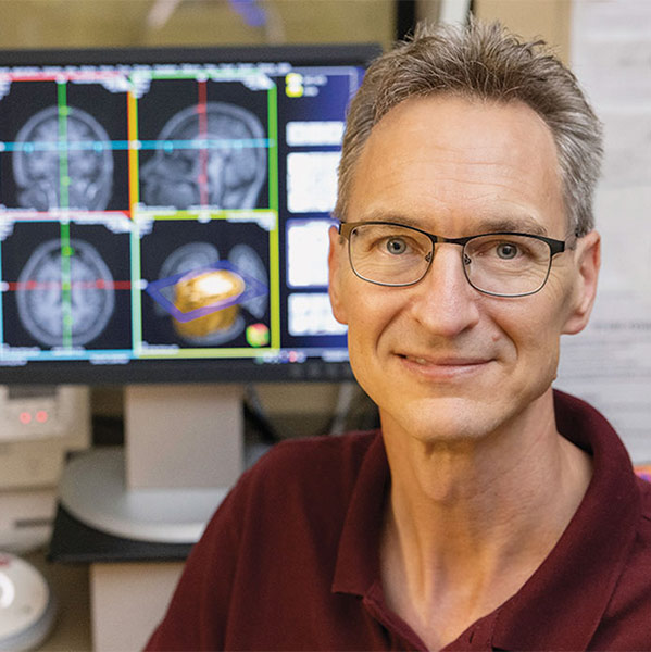 Chris Rorden in front of brain scans on computer terminals