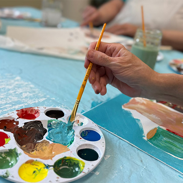 Paint brush in several colors of paint pallete