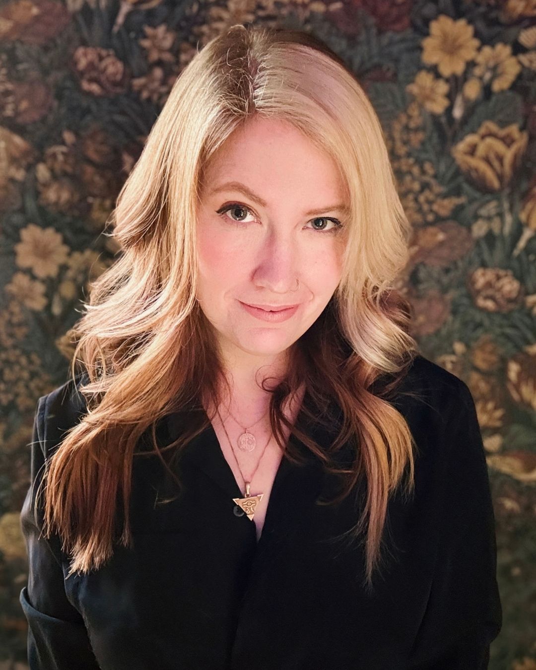 Ashley Poston smiles against a dark floral background.