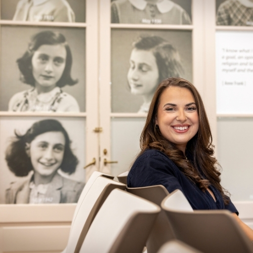 Sam Livonia smiles in the museum at USC's Anne Frank Center. Historic images of the Holocaust victim are on the wall behind Sam. 