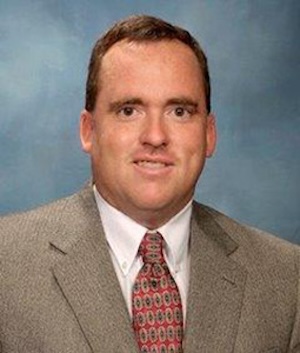 man in tan suit and garnet tie