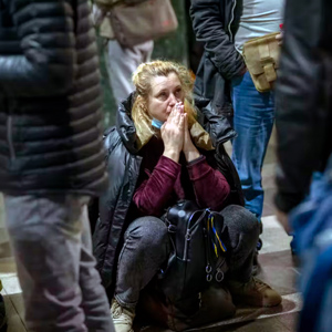 A woman in Ukraine appears to pray as she waits for a train out of Kyiv
