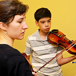 Undergraduate student teaches her student a string instrument