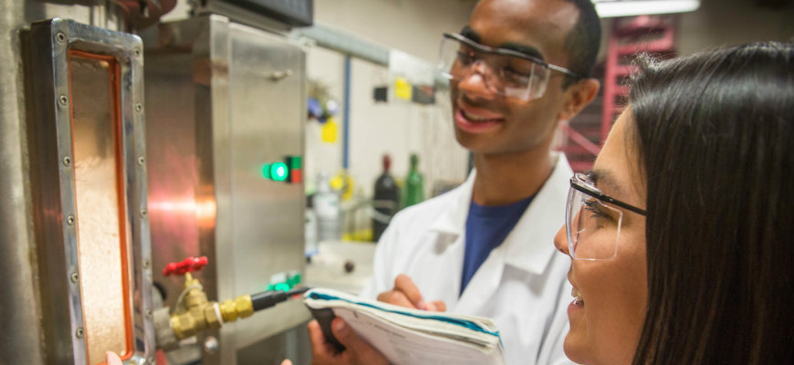 Students look at a machine during experiment.